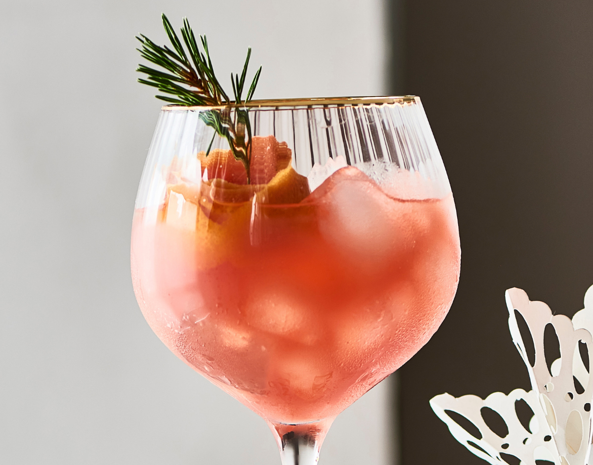 Pynt din julecocktail med en strimmel rød grapeskal og en kvist gran