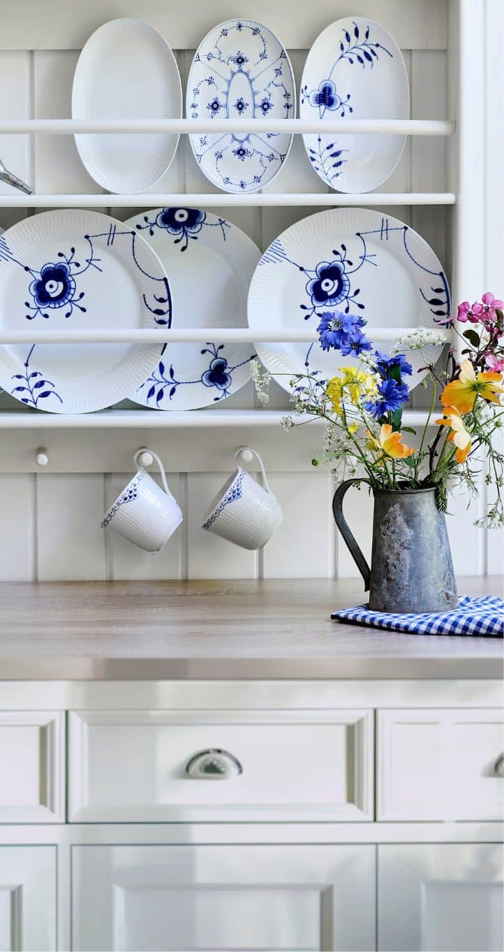 Tallerkenrække med stel fra Royal Copenhagen og kande med blomster