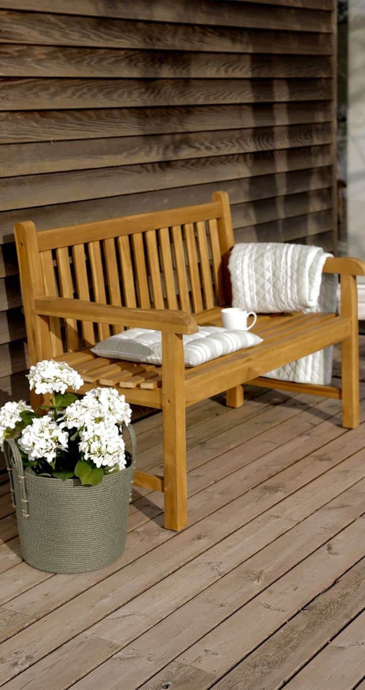 Blåvand havebænk fra Skagen Living på træterrasse med blomster og tæppe